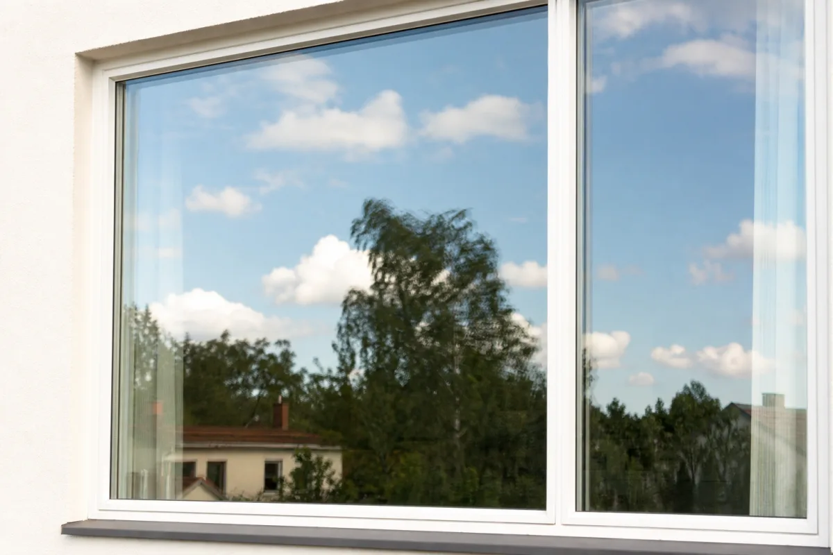 F&ouml;nster med spegelfilm sett utifr&aring;n mitt p&aring; dagen, glaset reflekterar himmel och fasad ist&auml;llet f&ouml;r att visa rummet innanf&ouml;r